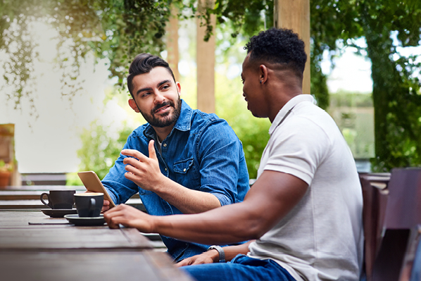 two male friends sitting at a patio table outside